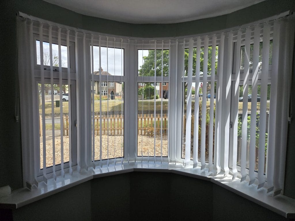 White vertical blinds fitted in a curved bay window