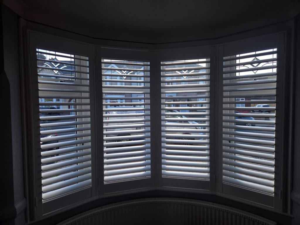 White plantation shutters installed in a curved bay window